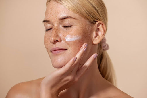 Woman using skin care cream on her face with a subtle smile and closed eyes 